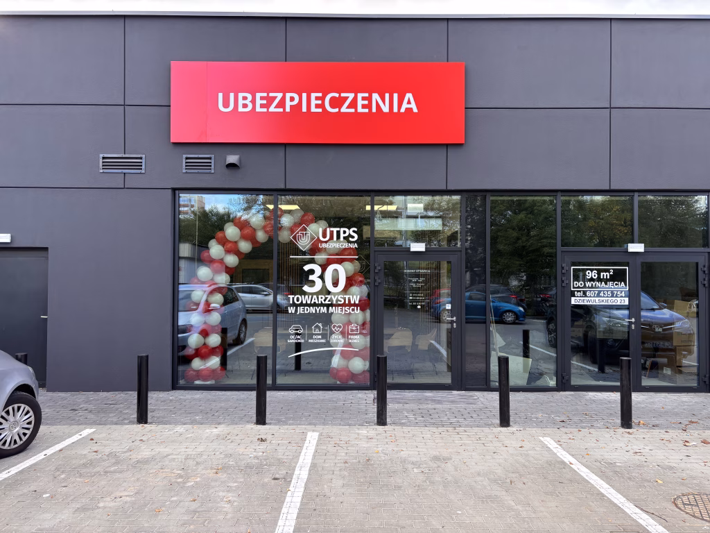 Biuro UTPS Ubezpieczenia, z banerem reklamowym ubezpieczenia, budynek jest z elewacją w kolorze grafitowym.